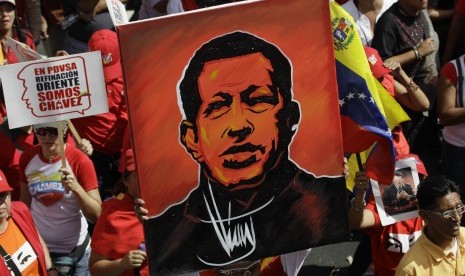   Seorang pendukung Presiden Venezuela Hugo Chavez mengangkat sebuah lukisan dirinya saat pelantikan secara simbolis Presiden Venezuela Hugo Chavez diluar Istana Presiden Miraflores di Caracas,Venezuela,Kamis (10/1).   (AP/Fernando Llano)