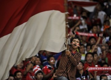 Seorang pendukung tim nasional Indonesia mengibarkan bendera merah putih dalam laga leg kedua kualifikasi Piala Dunia 2014 Zona Asia antara Indonesia vs Turkmenistan di Stadion Gelora Bung Karno, Senayan, Jakarta, beberapa waktu lalu.