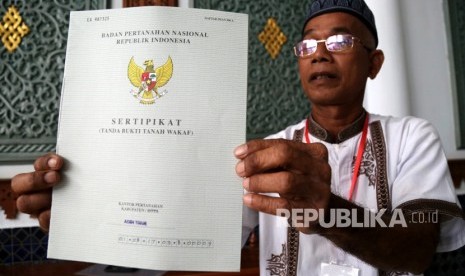 Seorang penerima memperlihatkan sertifikat tanah wakaf masjid, mushola, dan pasantren yang diserahkan Presiden Joko Widodo seusai melaksanakan ibadah Jumat di Banda Aceh, Aceh, Jumat (14/12/2018).