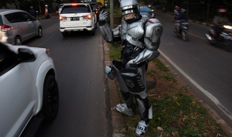 Seorang pengamen mengenakan kostum Robocop saat mengamen di kawasan Jalan Juanda, Depok, Jawa Barat, Kamis (30/3). 