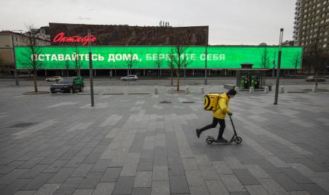 Seorang pengantar makanan melintasi New Arbat Avenue yang sepi di Moskow, Rusia, Kamis (30/4). Amerika Serikat menyatakan siap membantu Rusia mengatasi pandemi corona.