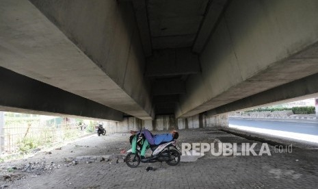  Seorang pengemudi ojek online beristirahat untuk melepas kantuknya di kolong flyover Pramuka Jakarta, Ahad (3/9). 