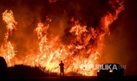 Seorang pengendara di Jalan Tol  Highway 101 menonton 'Thomas Fire' (kebakaran yang melanda California) 'menyeberangi' jalan  Ventura, California, Amerika Serikat.