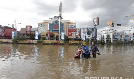 Seorang pengendara mendorong motornya Yang mogok akibat melintas di banjir yang terjadi di kawasan Simpang Lembuswana, Samarinda, Kalimantan Timur, Senin (10/6/2019).