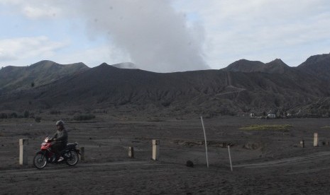 Seorang pengendara motor melintas di kawasan kaldera Gunung bromo yang mengeluarkan material debu vulkanik dan asap putih keabu-abuan di Probolinggo, Jawa Timur, Selasa (27/9). 