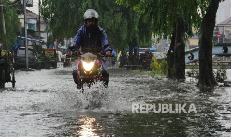 Seorang pengendara sepeda motor, menerobos genangan air di Jl Sunter Kemayoran Jakarta, yang digenangi air hujan air kali Item yang mulai tumpah ke jalan, Selasa (21/2). 