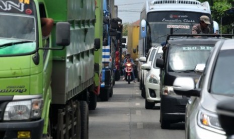 Seorang pengendara sepeda motor terjebak di antara kendaraan mobil yang terjebak macet di jalur pantura, Selasa (22/12)