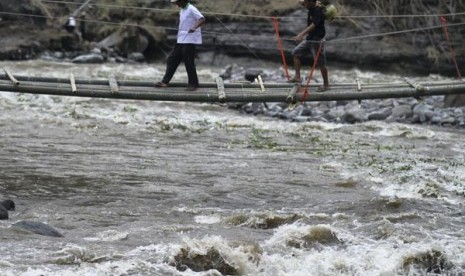 Seorang pengungsi melintasi jembatan darurat yang dibangun di dusun Klangon, Pandansari, Ngantang, Malang, Jawa Timur, Sabtu (22/2). Jembatan tersebut dibangun sementara untuk menggantikan jembatan utama penghubung dusun Klangon dengan akses jalan utama ya