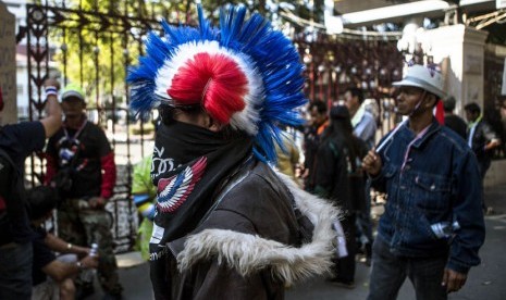  Seorang pengunjuk rasa anti-pemerintah, dengan rambut mohawk yang berwarna, berkumpul bersama pengunjuk rasa lainnya di dekat pintu gerbang markas Polisi Kerajaan Thailand di pusat kota Bangkok  (15/1).   (Reuters/Nir Elias)