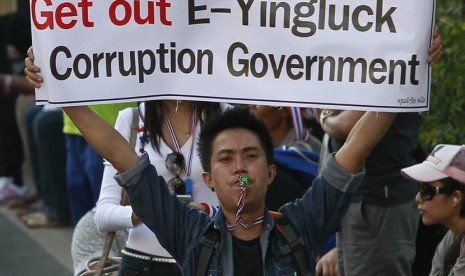  Seorang pengunjuk rasa anti-pemerintah meniup peluitnya sambil memegang poster saat berunjuk rasa di pusat kota Bangkok (15/1).    (Reuters/Chaiwat Subprasom)