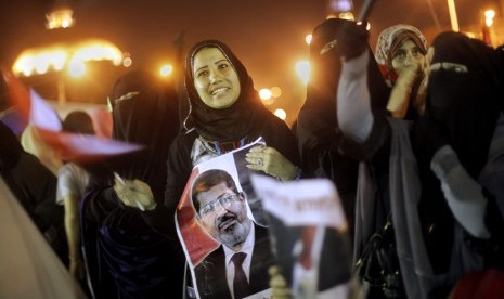 Seorang pengunjuk rasa memegang poster Presiden Mursi saat berunjuk rasa menolak kudeta militer di dekat Universitas Kairo, Senin (15/7).     (AP/Amr Nabil)