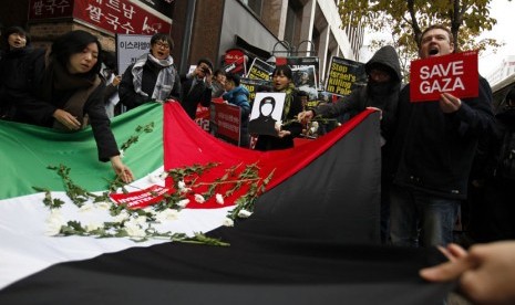  Seorang pengunjuk rasa menempatkan bunga pada bendera nasional Palestina dalam aksi demonstrasi mengutuk operasi militer Israel terhadap Jalur Gaza, di depan kedutaan Israel di Seoul, Jumat (16/11).  (Reuters/Kim Hong-Ji)