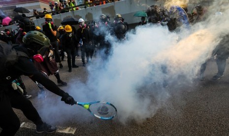 Seorang pengunjuk rasa menggunakan raket tenis untuk mengembalikan tabung gas air mata ketika polisi anti huru hara menembakkan gas air mata untuk membubarkan pengunjuk rasa di Hong Kong, Cina, Ahad (15/9). 