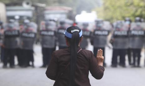 Seorang pengunjuk rasa wanita memberikan hormat tiga jari di depan polisi di Mandalay, Myanmar, Sabtu, 20 Februari 2021. Pasukan keamanan di Myanmar meningkatkan tekanan mereka terhadap pengunjuk rasa anti-kudeta Sabtu, menggunakan meriam air, gas air mata, ketapel dan peluru karet melawan para demonstran dan pekerja dermaga yang mogok di Mandalay, kota terbesar kedua di negara itu.