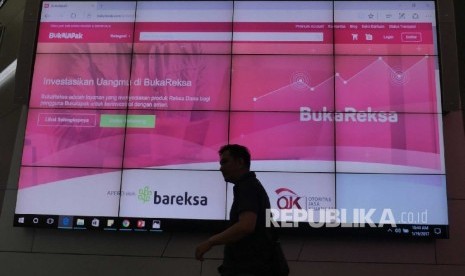  Seorang pengunjung melintasi layar monitor di sela peluncuran Buka Reksa di Gedung Bursa Efek Indonesia, Kamis (19/1). 