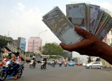 Seorang penjual jasa penukaran uang menjajakan uang pecahan di pinggiran Jalan Gajah Mada, Jakarta, Selasa (23/8). 