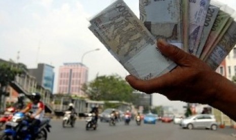 Seorang penjual jasa penukaran uang menjajakan uang pecahan di pinggiran Jalan Gajah Mada, Jakarta, Selasa (23/8). 