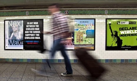  Seorang penumpang berjalan melewati sebuah poster anti-Islam yang dipasang di stasiun kereta bawah tanah Times Square, New York, Senin (24/9). Polisi New York Selidiki Serangan Terhadap Wanita Muslim di Kereta. (Bebeto Matthews/AP)