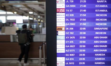 Seorang penumpang pesawat antre di loket dekat papan jadwal penerbangan di Terminal 3 Bandara Internasional Soekarno-Hatta, Tangerang, Banten.