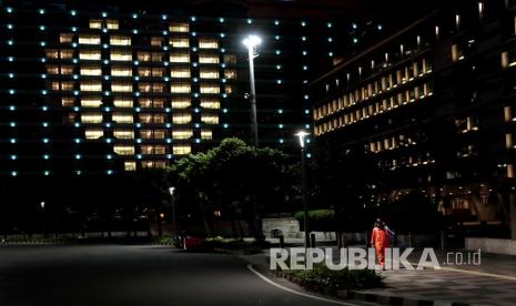  Seorang penyapu jalan berjalan melewati Hotel Indonesia Kempinski, ketika lampu kamar membuat bentuk hati untuk menghormati perawatan kesehatan dan pekerja penting lainnya masih bekerja, selama wabah coronavirus baru di Jakarta, Indonesia, Jumat (17/4/2020). Tenaga medis adalah kelompok kerap kali terpapar corona akibat ketidakjujuran pasien.