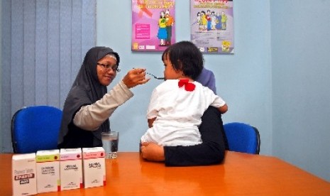 Seorang perawat tengah memberikan cairan Anti Retroviral Virus (ARV) sebagai obat memperlambat perkembangan virus kepada anak dengan HIV/AIDS.