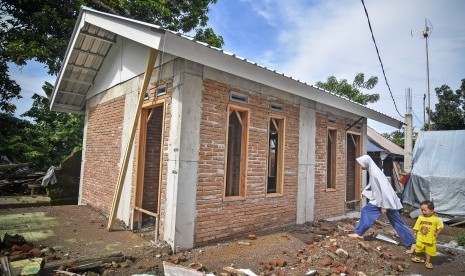 Seorang perempuan berjalan dekat bangunan Rumah Instan Sederhana Sehat (RISHA) untuk korban gempa di Desa Kekait, Kecamatan Gunungsari, Lombok Barat, NTB, Selasa (29/1/2019). 