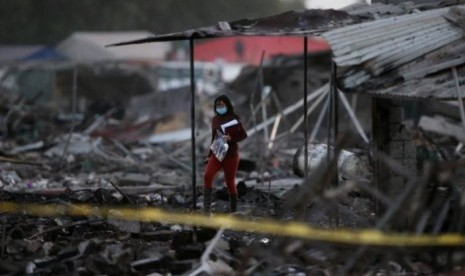 Seorang perempuan berjalan di tengah puing-puing rumah yang hancur akibat ledakan di pasar kembang api San Pablito di Tultepec, Meksiko, 20 Desember 2016.