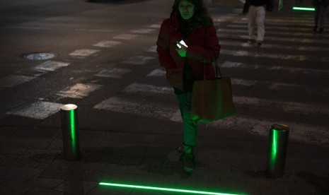  Seorang perempuan Israel berjalan melewati zebra cross yang telah dipasangi LED lampu lalu lintas yang disebut sebagai Lampu Zombie, Rabu (13/3). Lampu ini dipasang untuk memandu langkah pecandu ponsel yang terus menunduk saat hendak menyeberang.