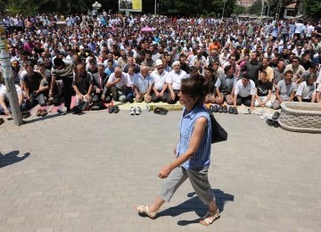 Seorang perempuan melenggang di hadapan ratusan jamaah shalat Jumat di jalan. Muslim Kosovo memprotes pemerintah ingin dibangunkan masjid yang representatif.