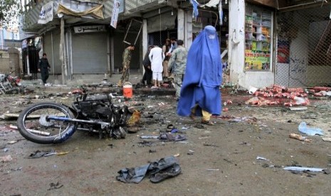 Seorang perempuan melintas di lokasi ledakan bom bunuh diri di Jalalabad, Sabtu (18/4).