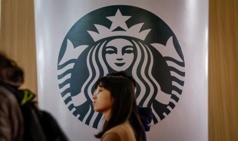 Seorang perempuan melintasi logo Starbucks di Beijing, China. Starbucks telah dituntut untuk ketiga kalinya oleh sebuah perusahaan yang menuduhnya mencuri konsep lipstik rasa kopi.