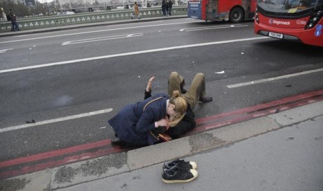 Seorang perempuan membantu korban luka di Westminster Bridge, London, Inggris, Rabu (22/3).