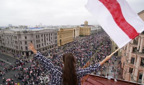 Seorang perempuan membawa bendera Belarus berdiri di atap sebuah bangunan di Minsk, Ahad (23/8). Belarus mencabut akreditasi sejumlah wartawan yang bekerja untuk media asing dan yang meliput protes anti pemerintah yang terjadi setelah pemilihan presiden yang bermasalah. 