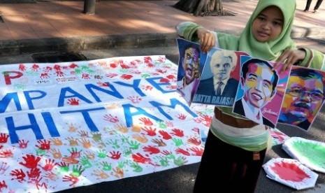 Seorang perempuan memegang sejumlah poster bergambar capres dan cawapres Pemilu 2014, saat aksi simpati 'STOP KAMPANYE HITAM' saat Car Free Day (CFD) di Taman Bungkul Surabaya, Ahad (1/6). 