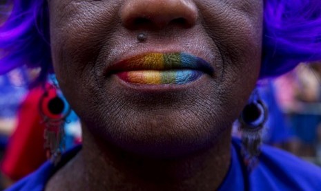 Seorang perempuan memoleskan warna pelangi, simbol kelompok LGBT, pada Parade Gay di New York (28/6).