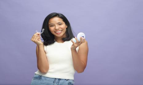 Seorang perempuan menunjukkan aligners yang dipakainya. Mempercantik gigi dengan kawat sudah kuno, kini tren bergeser dengan memakai aligners.