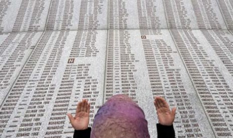 Seorang perempuan Muslim Bosnia berdoa di dinding peringatan berisi nama korban Pembantaian Srebrenica di Potocari Memorial Center.