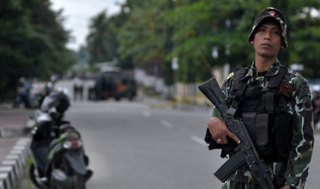 Seorang personil Brimob bersenjata lengkap berjaga-jaga di jalan raya tepat di depan markas Polsek Kota untuk menghalau warga sipil menuju tempat kejadian perkara (TKP) adanya benda diduga berisi bom, di Poso, Sulawesi Tengah, Rabu (11/3).