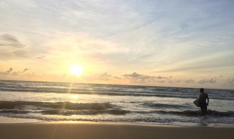 Seorang peselancar sedang berselancar di Pantai Carita, Banten, saat matahari terbenam, Sabtu (29/12). Sepekan setelah dihantam tsunami, aktivitas di Pantai Carita perlahan-lahan mulai pulih.