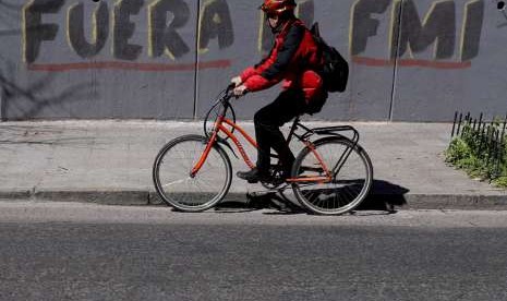 Seorang pesepeda melintasi grafiti berbahasa Spanyol di jalan di Buenos Aires, Argentina, Selasa (4/9). Grafiti tersebut berarti 'Pergilah IMF'. Beberapa pekan terakhir, krisis Argentina meningkat dan memaksa negara tersebut berutang ke IMF.