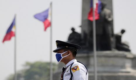 Seorang petugas di Manila mengenakan masker. Para wali kota dari 16 wilayah Metro Manila mengumumkan jam malam pada Sabtu dan mendesak mal-mal tutup selama sebulan. Ilustrasi.