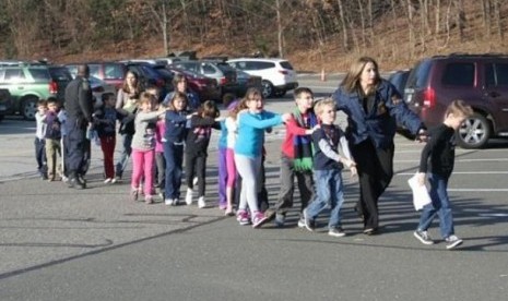 Seorang petugas keamanan mengawal murid-murid Sekolah Dasar Sandy Hook, Connecticut, AS, ke tempat aman, usai insiden penembakan di sekolah tersebut, Jumat (14/12/2012) menewaskan 26 orang.