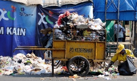 Seorang petugas kebersihan membersihkan sampah yang menumpuk di pinggir ruas Jalan Jend Ahmad Yani, Bandung, Jawa Barat.