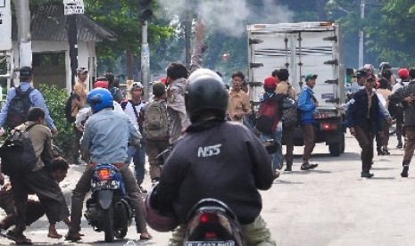 Seorang petugas kepolisian dan warga berusaha membubarkan pelajar pelaku tawuran di Jakarta (ilustrasi). 