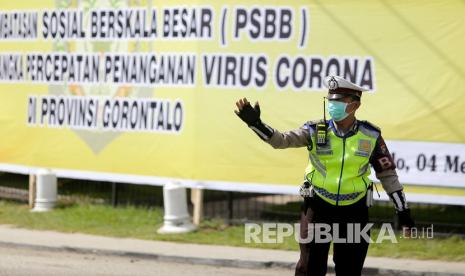 Seorang petugas kepolisian mengatur lalu lintas saat sosialisasi pencanangan Pembatasan Sosial Berskala Besar (PSBB) di Kota Gorontalo, Gorontalo, Senin (4/5/2020). Pemprov Gorontalo melakukan sosialisasi PSBB mulai tanggal 4-6 Mei dan akan diberlakukan secara resmi mulai tanggal 7 Mei 2020 nanti guna memutus mata rantai penyebaran COVID-19.