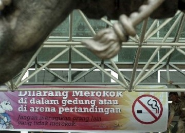 Seorang petugas memasang spanduk larangan merokok di area pertandingan SEA Games 2011.