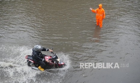 Seorang petugas memberikan arahan kepada pengguna jalan agar mengikuti arahannya saat melintas di kisaran jalan landas pacu timur kemayoran, Jakarta, yang digenangi air, Selasa (21/2)