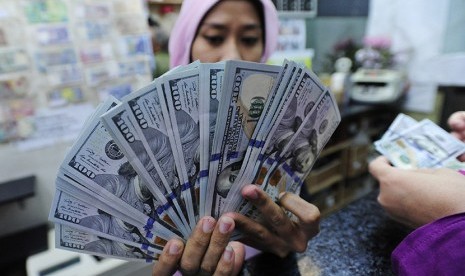 Seorang petugas memperlihatkan pecahan dolar AS yang akan ditukarkan di salah satu gerai penukaran mata uang asing di Jakarta, Senin (24/8).   (Antara/Wahyu Putro A)