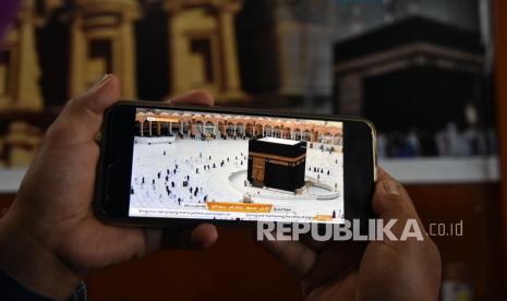 Seorang petugas menunjukan kondisi lengang disekitar Kabah saat ibadah Umroh di Arab Saudi disiarkan langsung lewat media sosial, saat hari pertama kembali beroperasinya kantor Muhibbah Tour, di Kota Pekanbaru, Riau, Selasa (3/11/2020). Perusahaan jasa keberangkatan haji dan umroh mulai buka kembali setelah Arab Saudi mulai mengizinkan warga negara lain untuk menunaikan Umroh sejak 1 November 2020, meski begitu biaya umroh mengalami kenaikan hingga 40 persen karena persyaratan protokol kesehatan yang diperketat pada masa pandemi. 