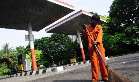 Seorang petugas menyapu lahan bekas stasiun pengisian bahan bakar umum (SPBU) di kawasan Pakubuwono, Jakarta Selatan, Ahad (1/5).